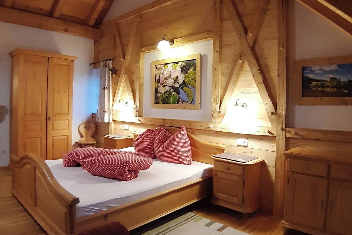 Un dormitorio de madera con una cama, una mesita de noche, un armario y un cuadro en la pared.