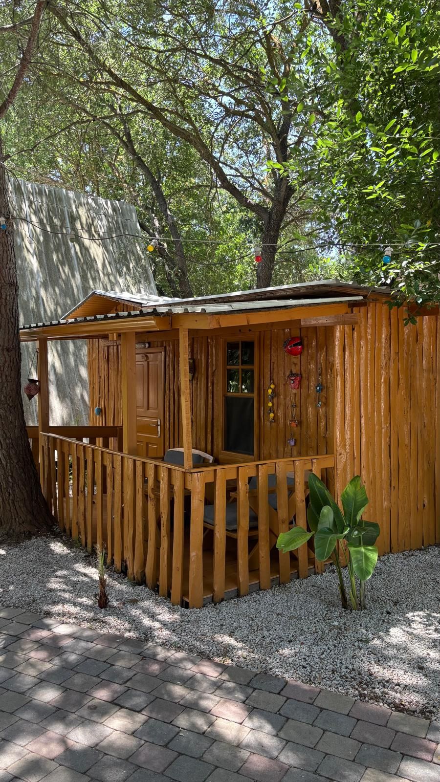 Una cabaña de madera con un porche, una ventana y una puerta.