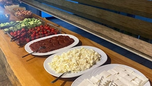 Una mesa de buffet con diferentes alimentos, como tomates, pepinos y queso.