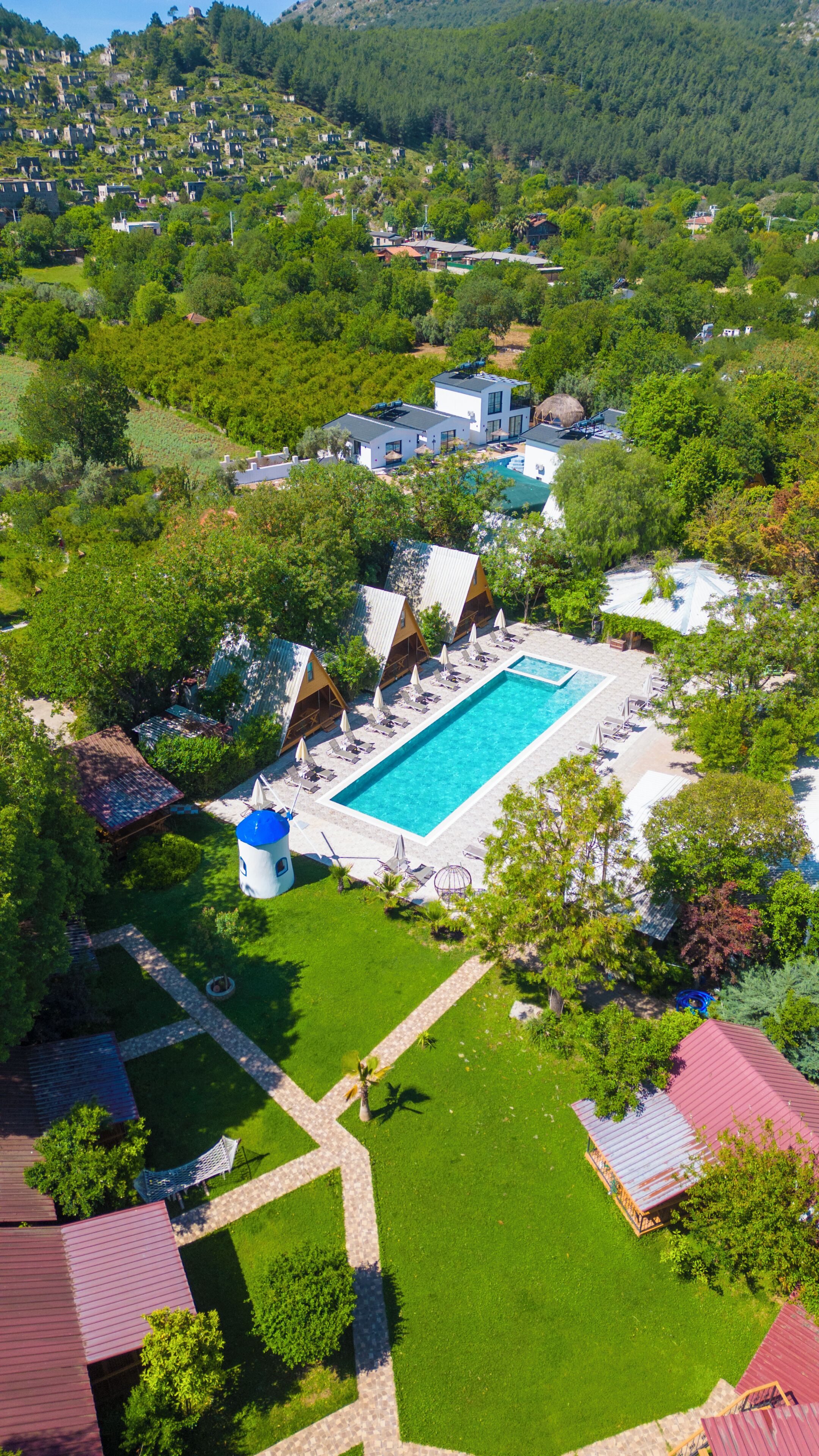 Ein Luftbild eines Resorts mit Schwimmbad, mehreren bungalowsähnlichen Unterkünften und einem gepflegten Rasen.