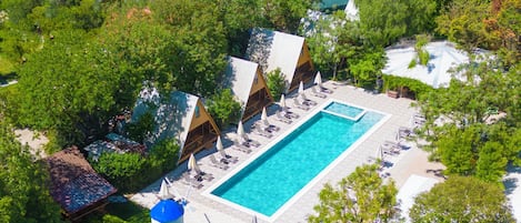 Vue aérienne d’un complexe hôtelier doté d’une piscine, de plusieurs hébergements de type bungalow et d’une pelouse bien entretenue.