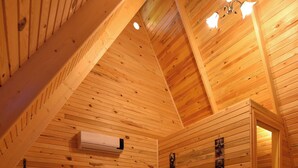 Una habitación acogedora de madera con cama, puerta y lámpara en el techo.