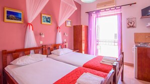 Een hotelkamer met twee bedden, een balkon, een televisie en een wastafel.