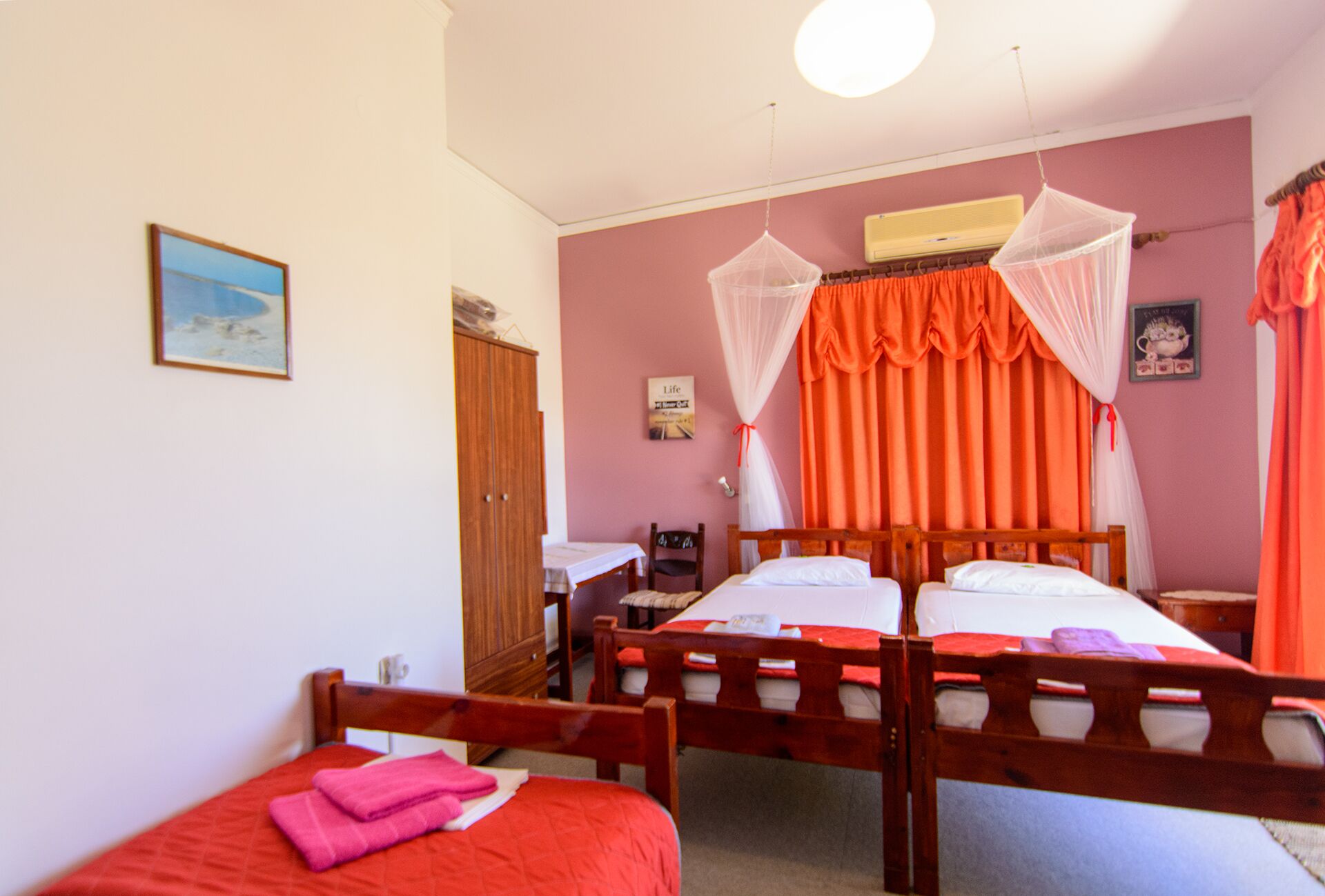 A bedroom with two wooden beds, a wooden wardrobe, a desk, and a chair.