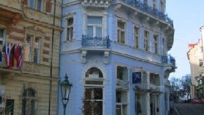 Un edificio en esquina con fachada blanca, múltiples ventanas y un balcón.