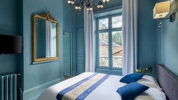 Une chambre à coucher avec un grand lit, un lustre, un miroir et une fenêtre avec des rideaux.