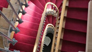 A spiral staircase with red carpeted steps and metal balusters.
