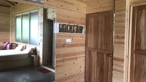 Ein Interieur einer Holzhütte mit einem Bett, einem kleinen Tisch und einem Spiegel.