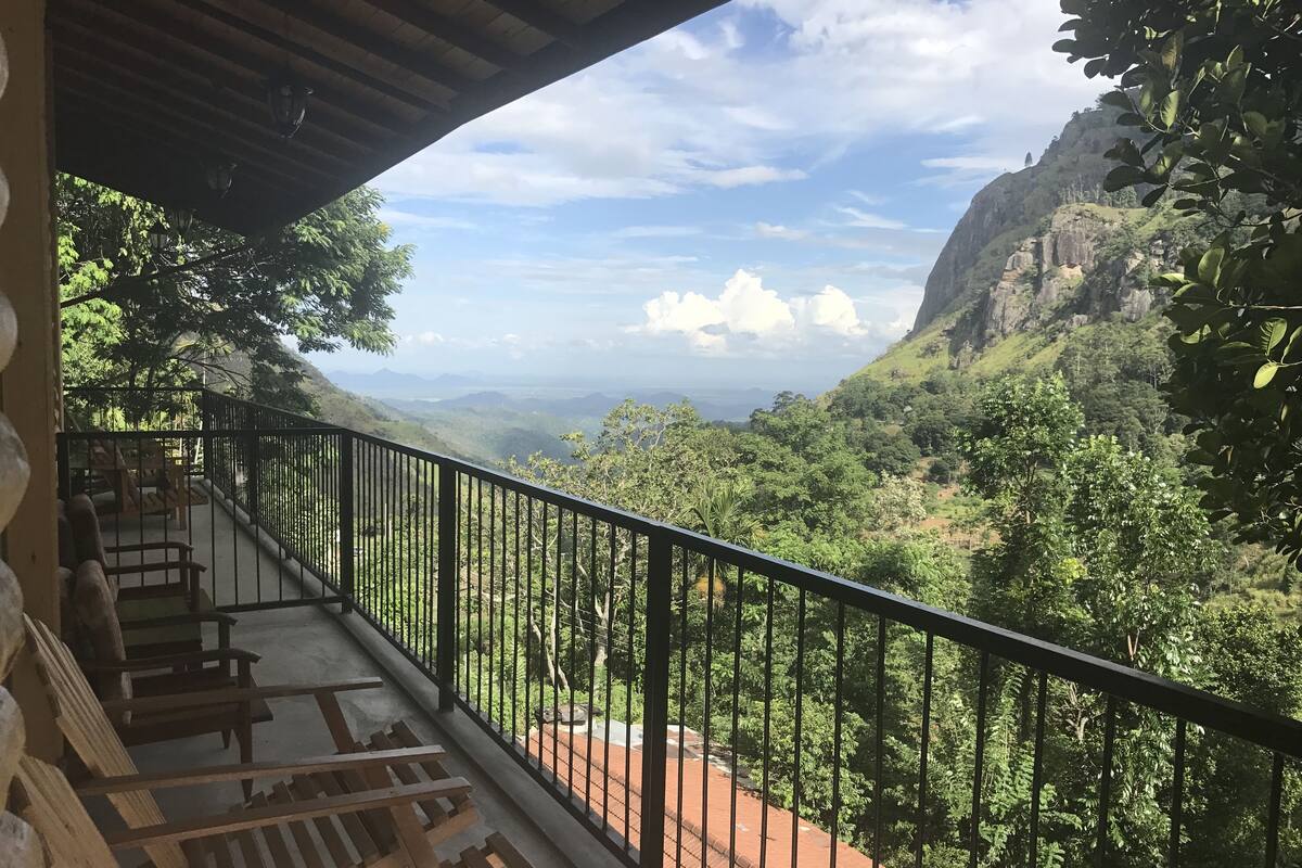 A balcony with a view of a lush valley and distant mountains.