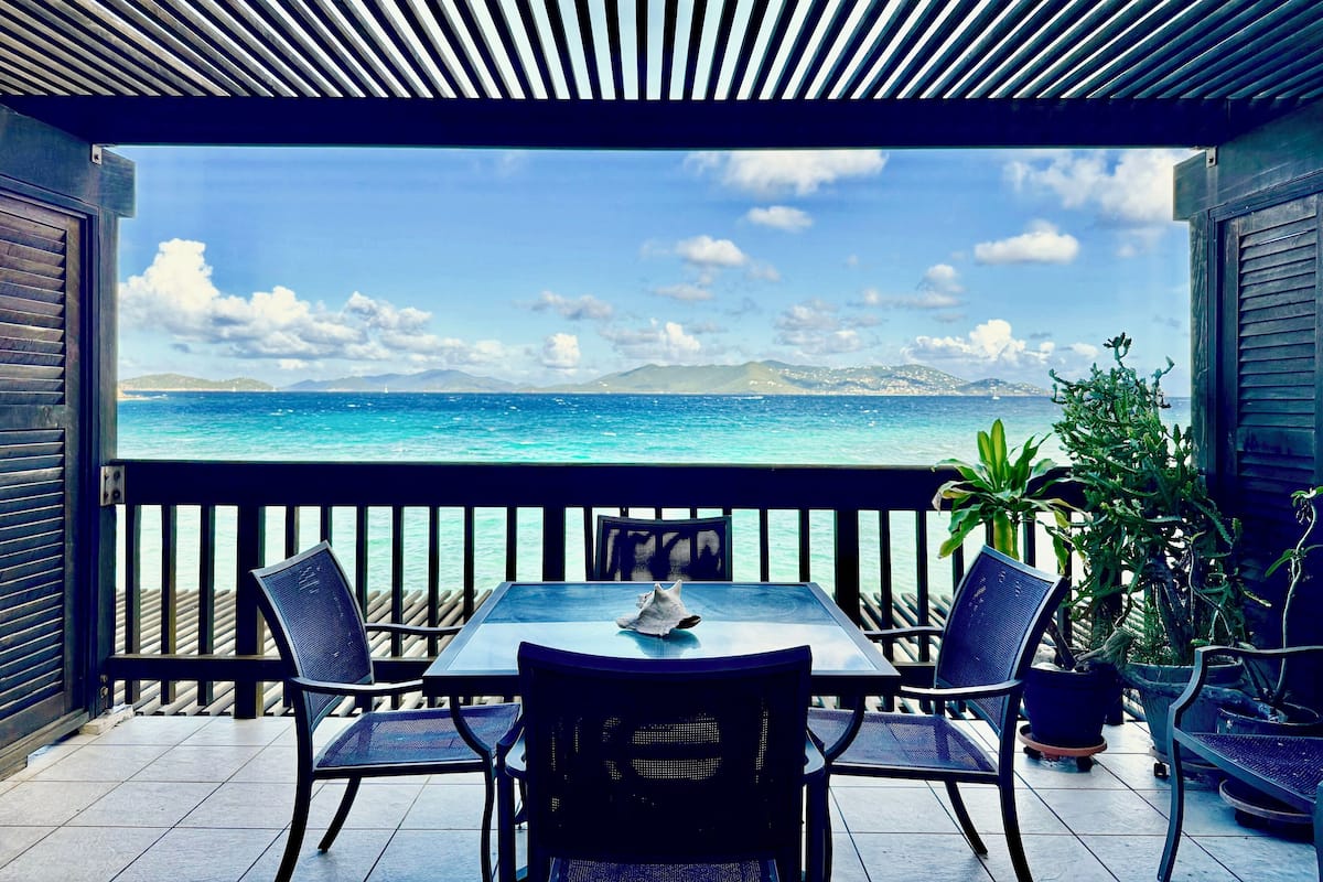 A terrace with a table and chairs overlooking a scenic ocean view.