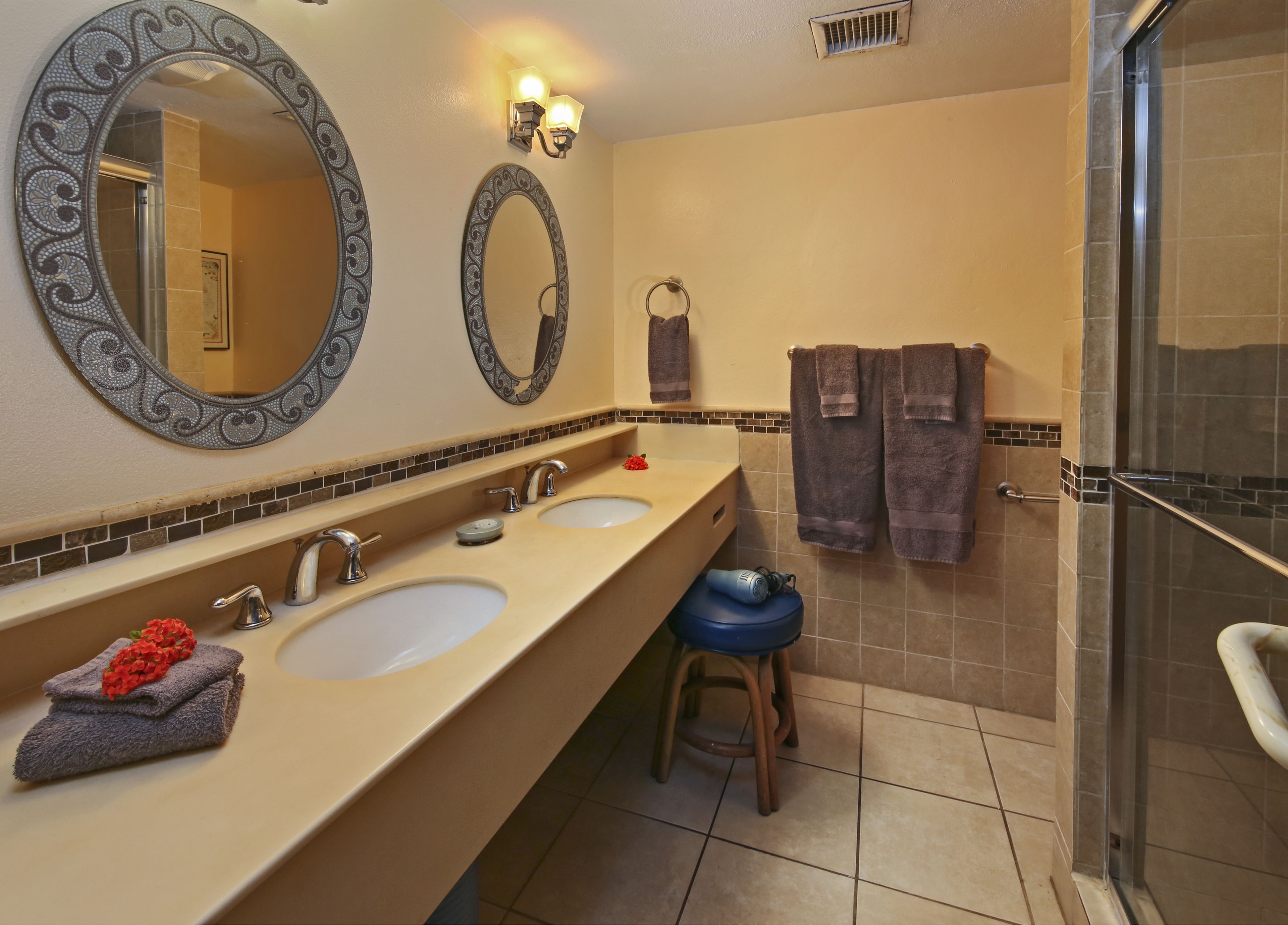 Un bagno con due lavandini, una doccia e due specchi a parete.