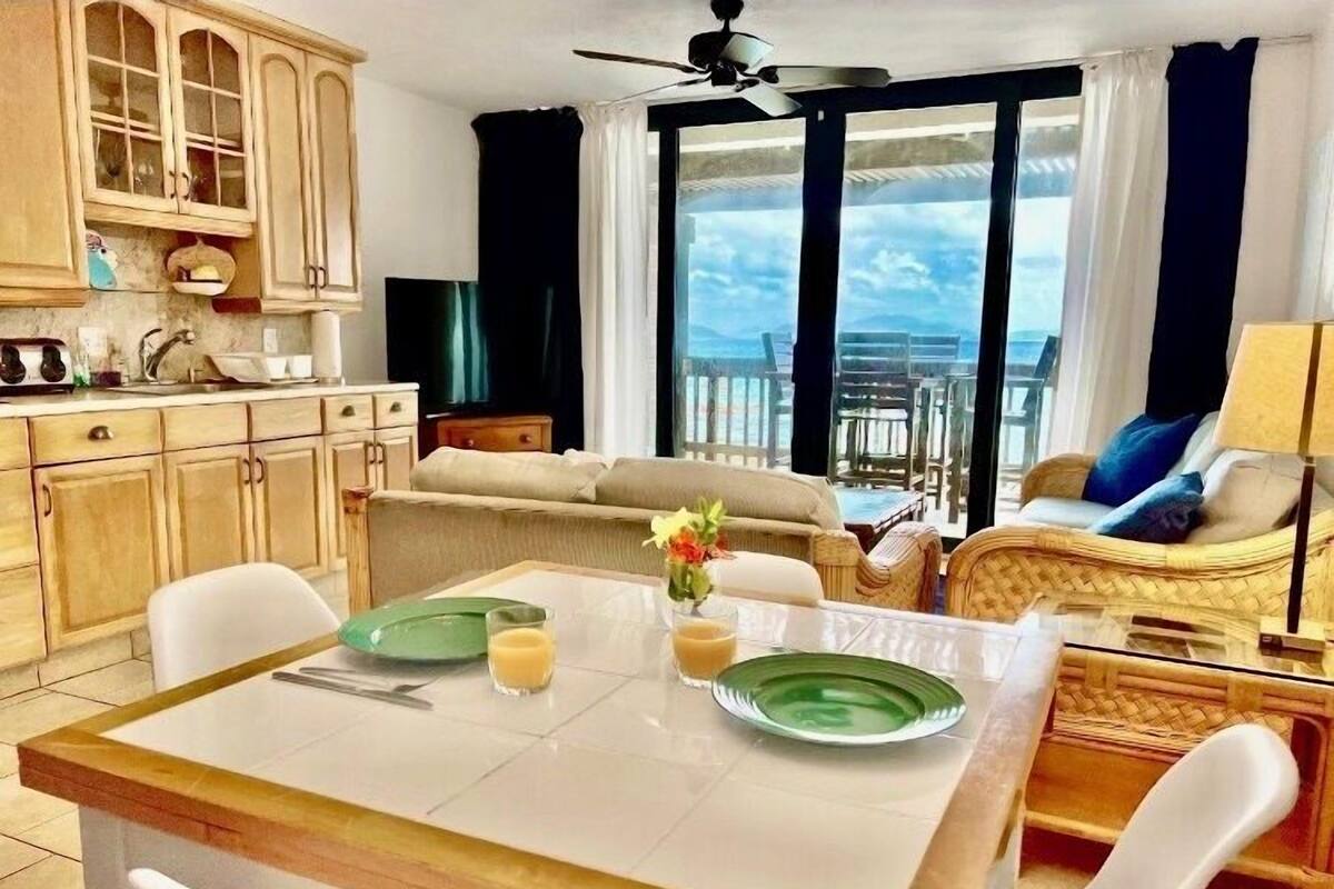 A dining area with a table, chairs, and a view of the ocean through large windows.