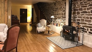 Een gezellige woonkamer met een stenen muur, houten vloeren, een open haard en een trap naar een andere kamer.