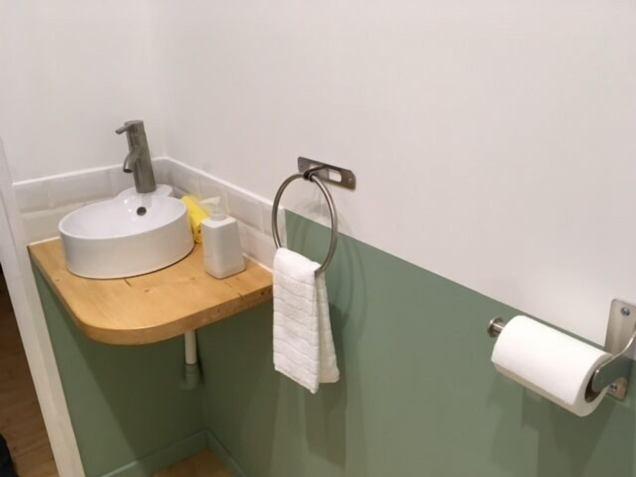 Un baño con lavamanos, una toalla y un dispensador de papel higiénico.