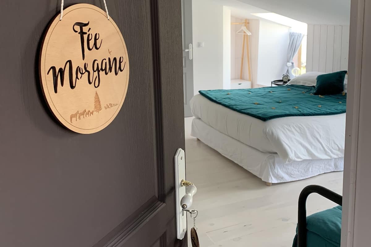 A bedroom with a bed, a bedside table, and a window.
