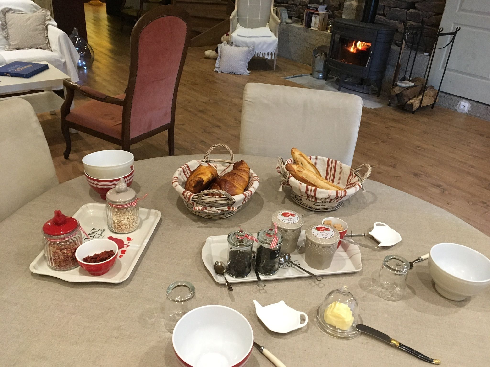 Una colazione con pane, pasticcini e condimenti su un tavolo in una stanza accogliente con camino.