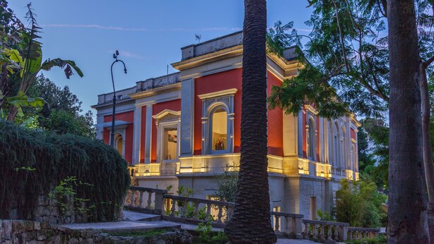 A historic building with classical architecture, featuring columns and a balcony.