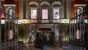 A grand entrance with ornate ironwork, a stone fireplace, and a balcony with a view of the interior.