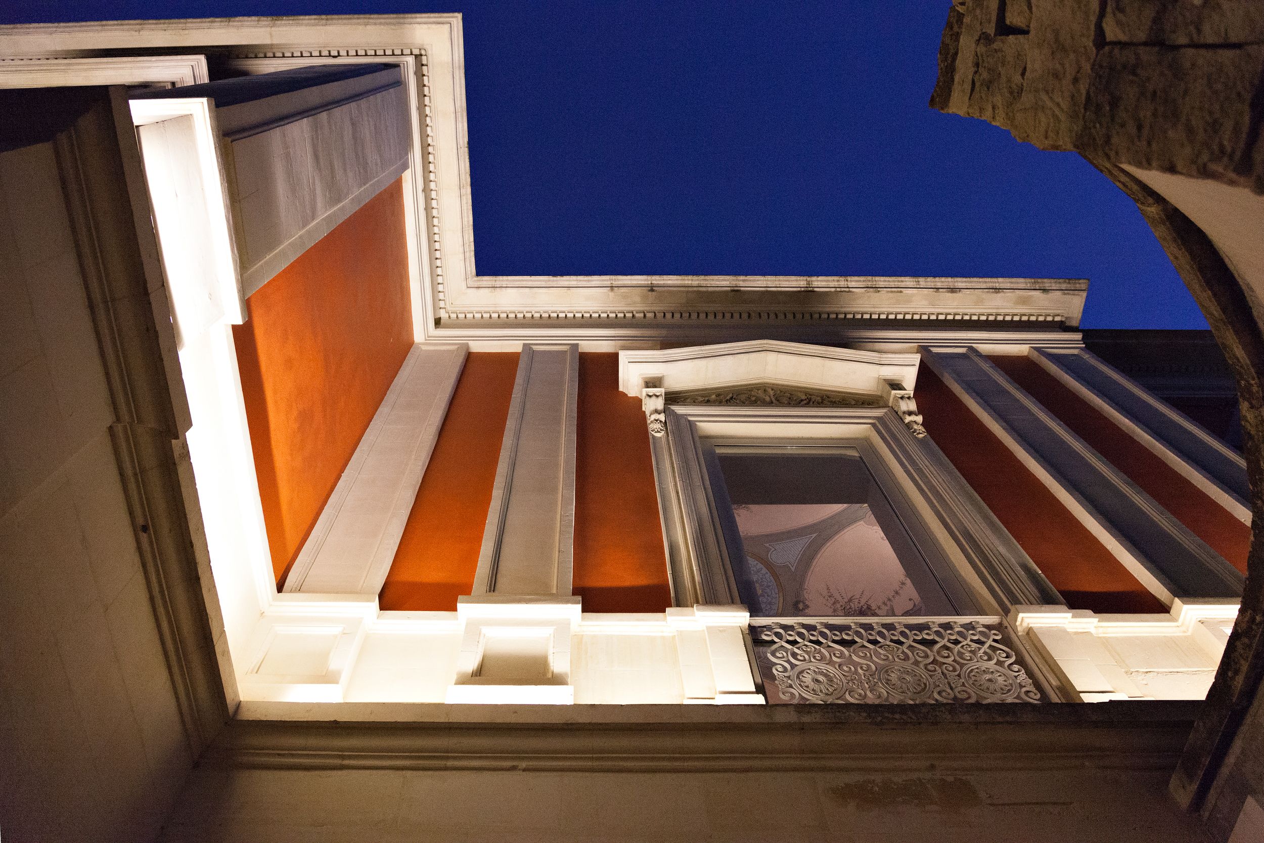 An architectural view of a building's interior with a staircase leading to a balcony.
