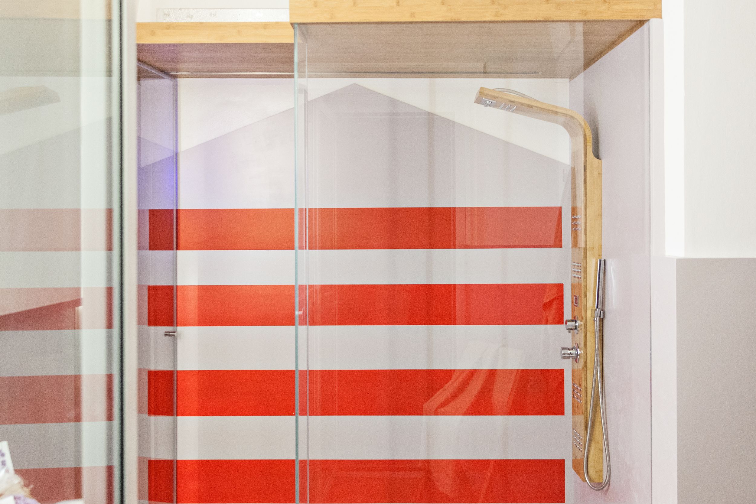A bathroom with a glass shower enclosure and a wooden showerhead.