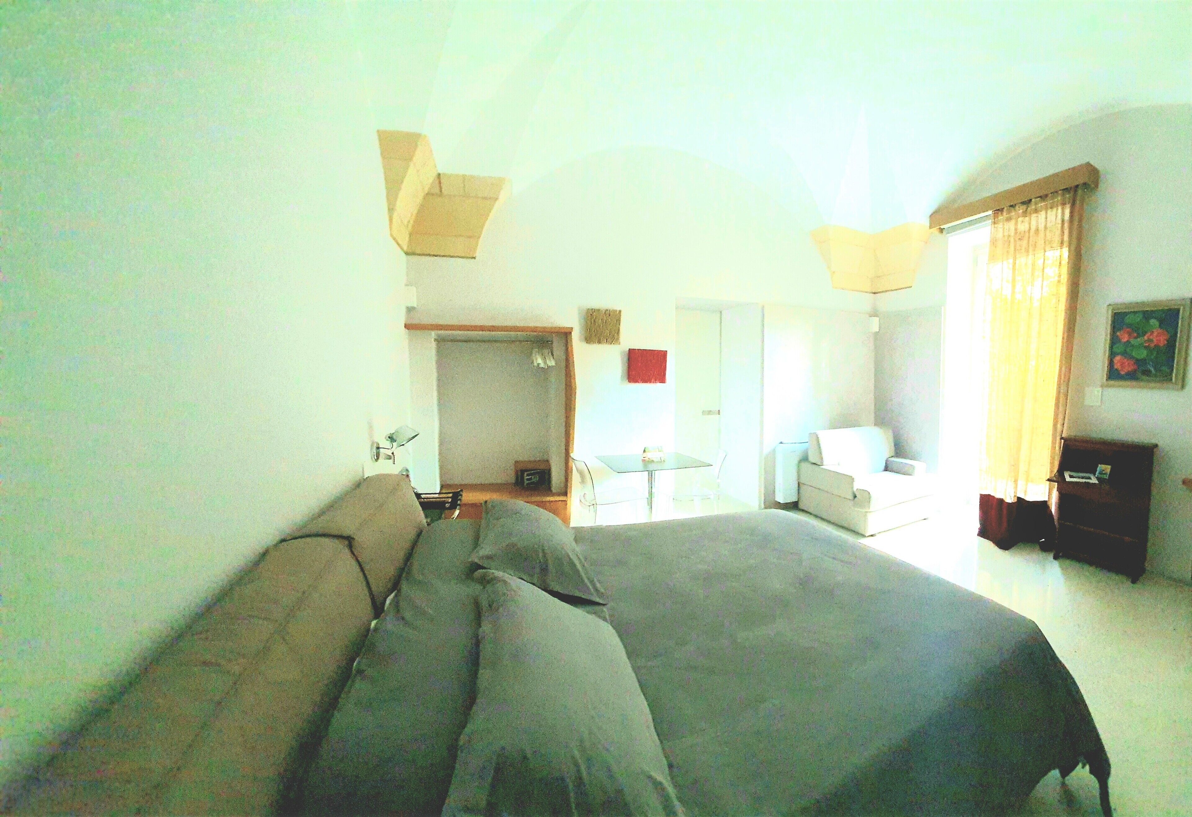A bedroom with a large bed, a desk, and a chair.