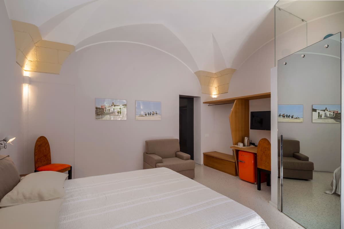 Habitació d'hotel amb un llit, escriptori, cadira, sofà i televisió.