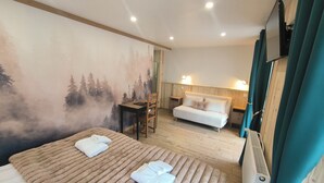 A hotel room with a bed, a desk, a chair, a sofa, and a TV. - Hôtel du Centre (Valloire)