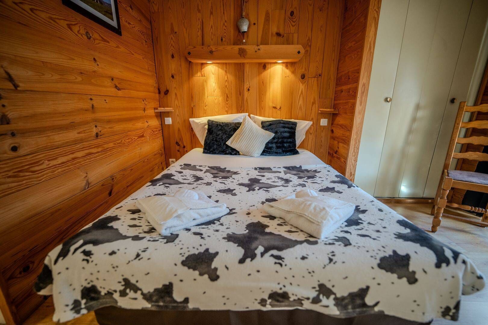 Une pièce de cabane en bois comprenant un lit, des oreillers et une chaise.