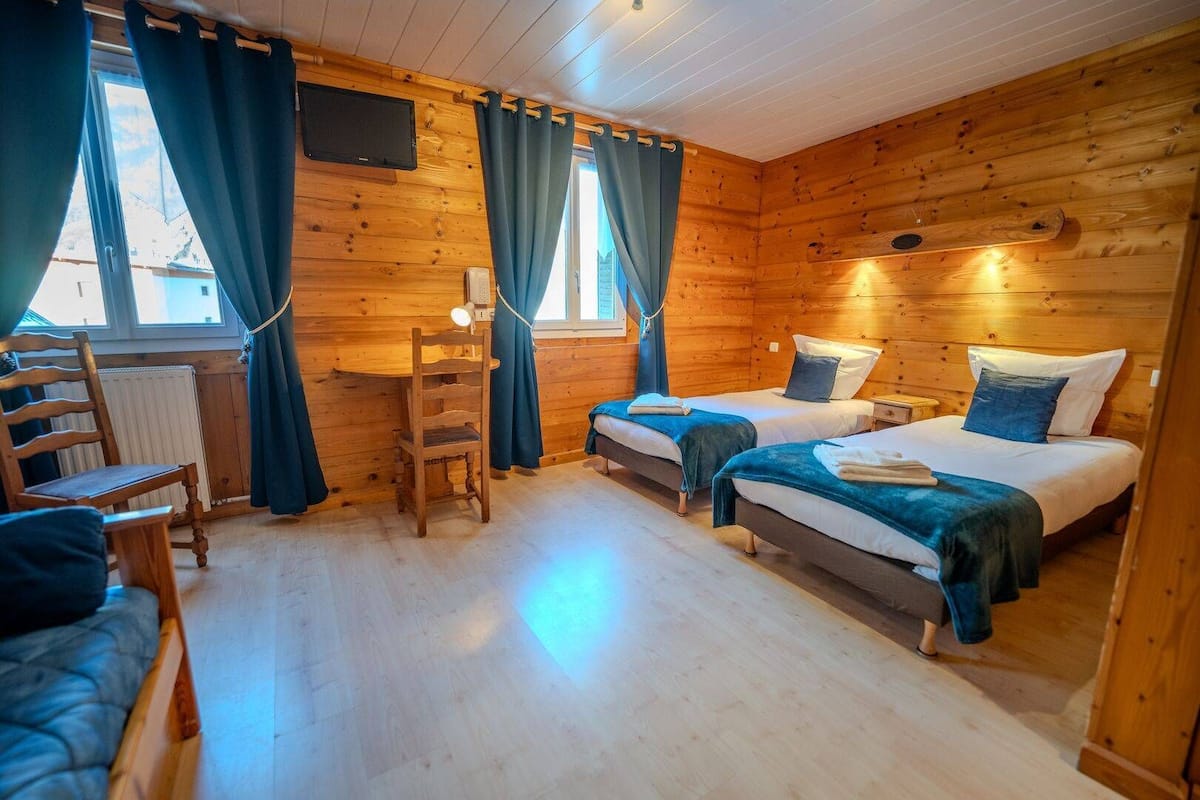 Una habitación de cabaña de madera con dos camas, un escritorio y una silla.