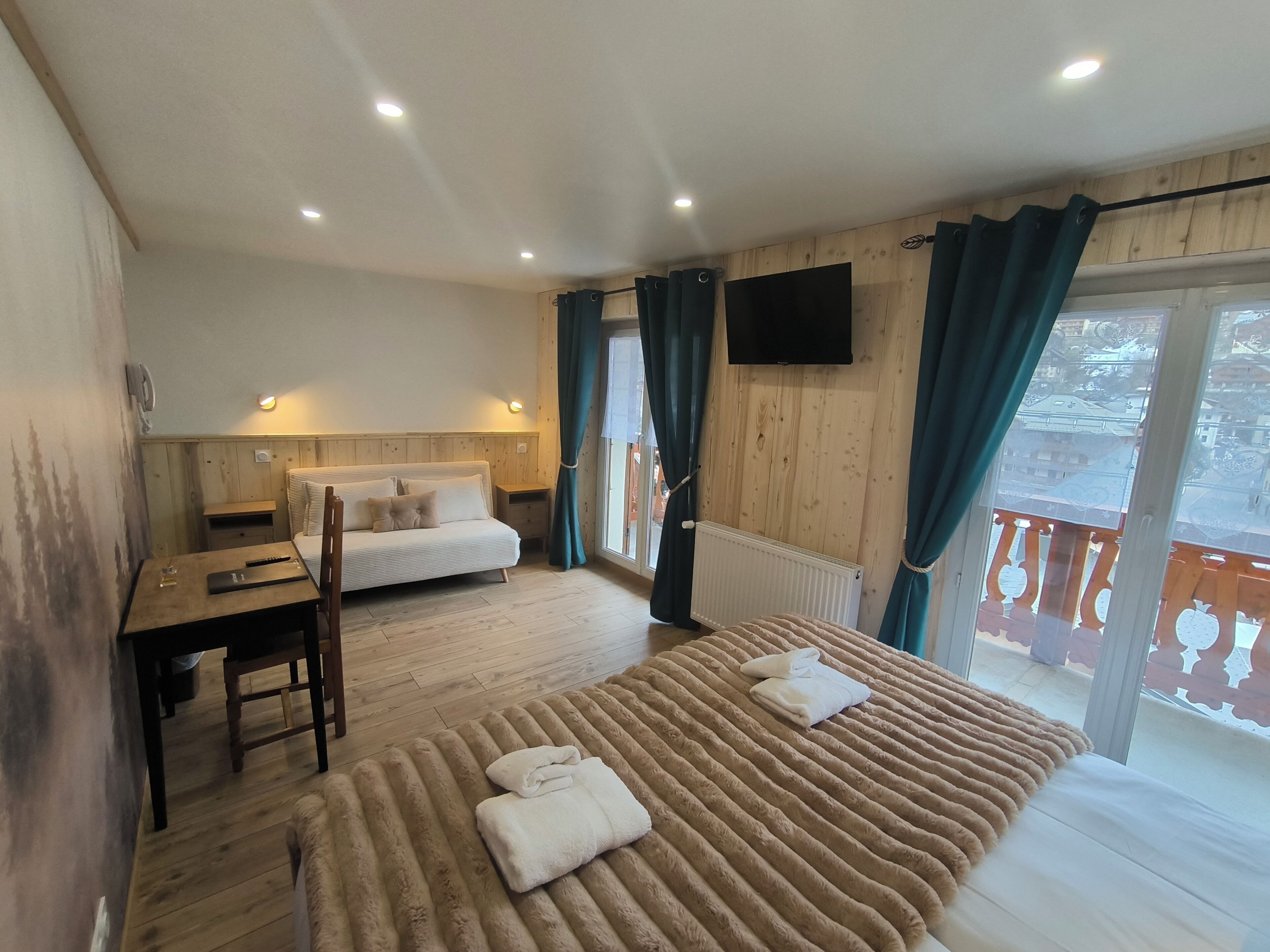 A room with a bed, a desk, a chair, a TV, and a window with curtains.
