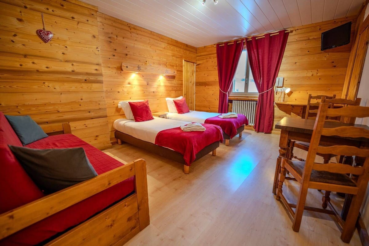 Una cabaña de madera con dos camas, una mesa de comedor y un televisor.