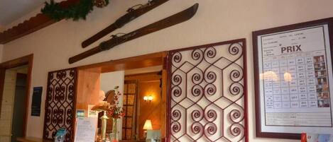 A reception area with a wooden counter, a framed price list, and decorative wall panels.