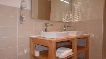 A bathroom with two sinks, a mirror, and a wooden vanity with shelves.