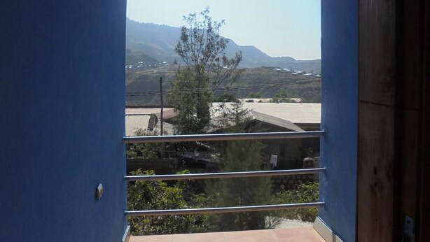 Un balcón con vista a montañas lejanas y un cielo despejado.