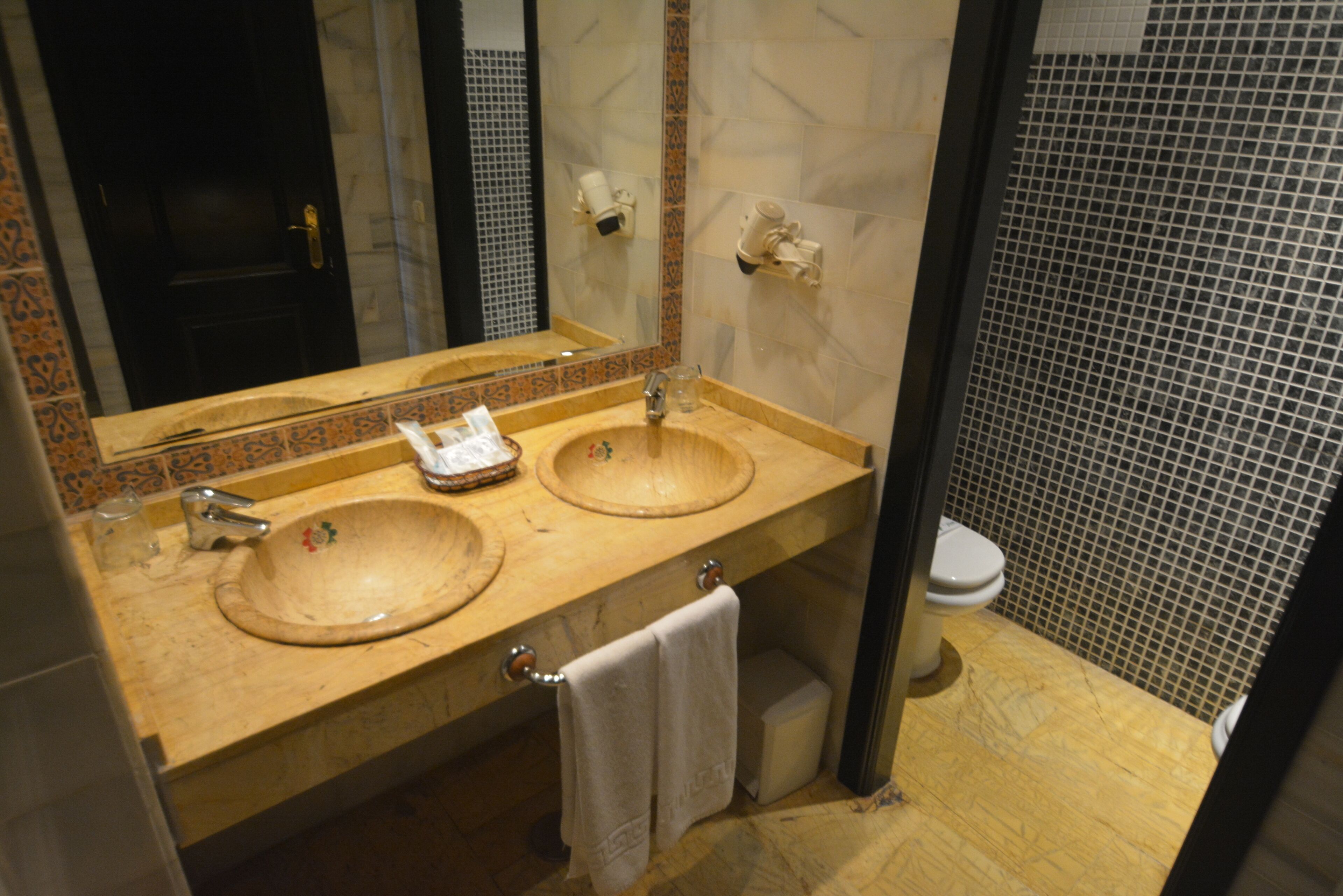 Een badkamer met twee wastafels, een toilet en een spiegel.