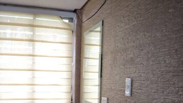 Un baño con un lavabo blanco, una ventana con persianas y una pared con textura.