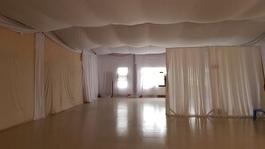 Una habitación amplia y vacía con techos altos y cortinas blancas.