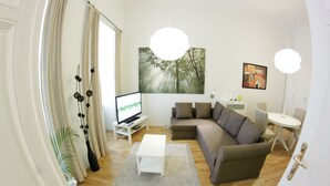 A modern living room with a sofa, a coffee table, a TV, and a painting on the wall. - Vienna Hotspot - Museum (Vienna)