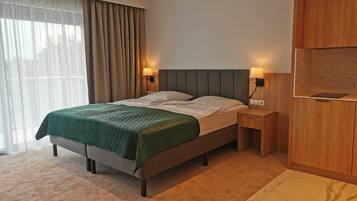 Ein modernes Hotelzimmer mit einem Bett, einem Holzschrank und einem Nachttisch mit Lampe.
