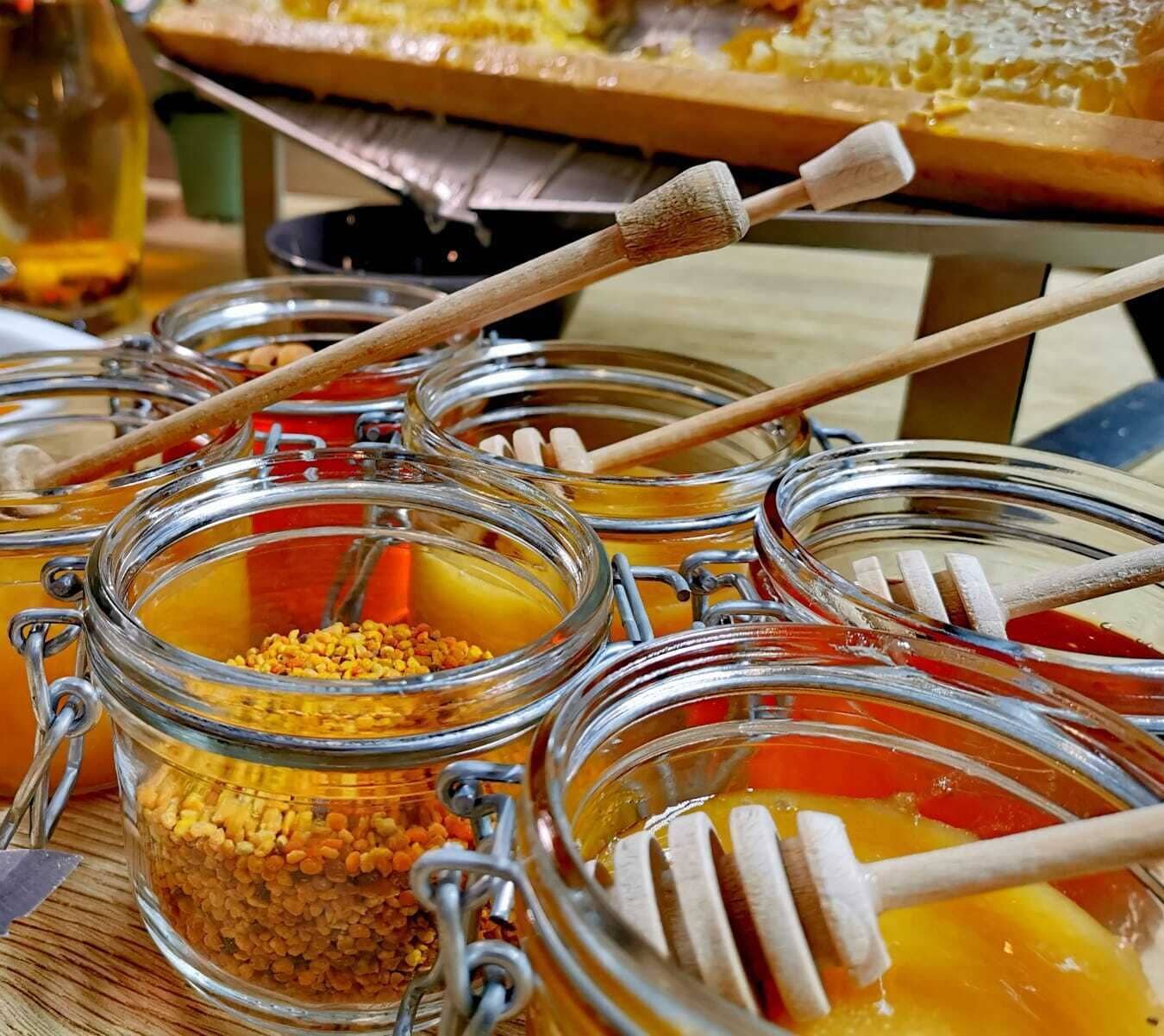 A buffet table with various food items in glass jars, including honey and granola.