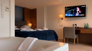 Una habitación de hotel con una cama, un escritorio, un televisor y una silla.