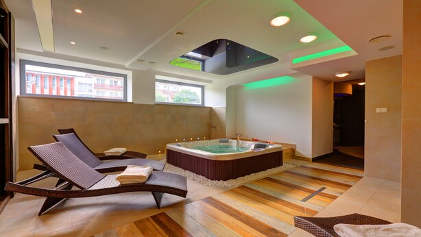 Een moderne spa met een jacuzzi, lounge stoelen en een houten vloer.