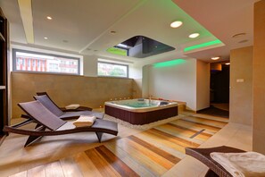 Une salle de spa moderne dotée d’un jacuzzi, de chaises longues et d’un plancher en bois.