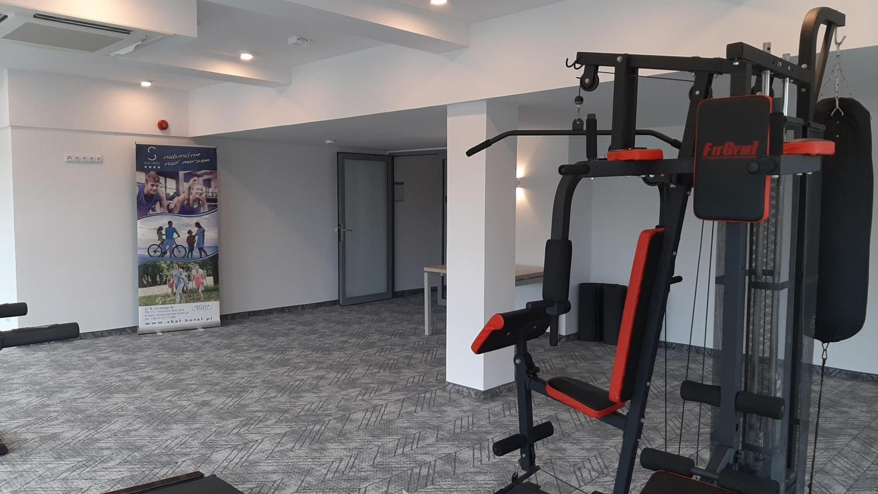 Un área de gimnasio con una máquina de ejercicios multifuncional que dice "FitGym".