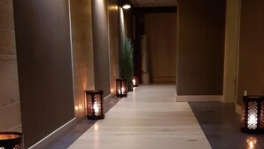 Een gang met een licht houten vloer, wanden met een donkere afwerking en decoratieve lantaarns langs de zijkanten.