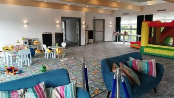 Un área de juegos infantiles con una mesa de fútbol de mesa, un tobogán y esterillas de colores.