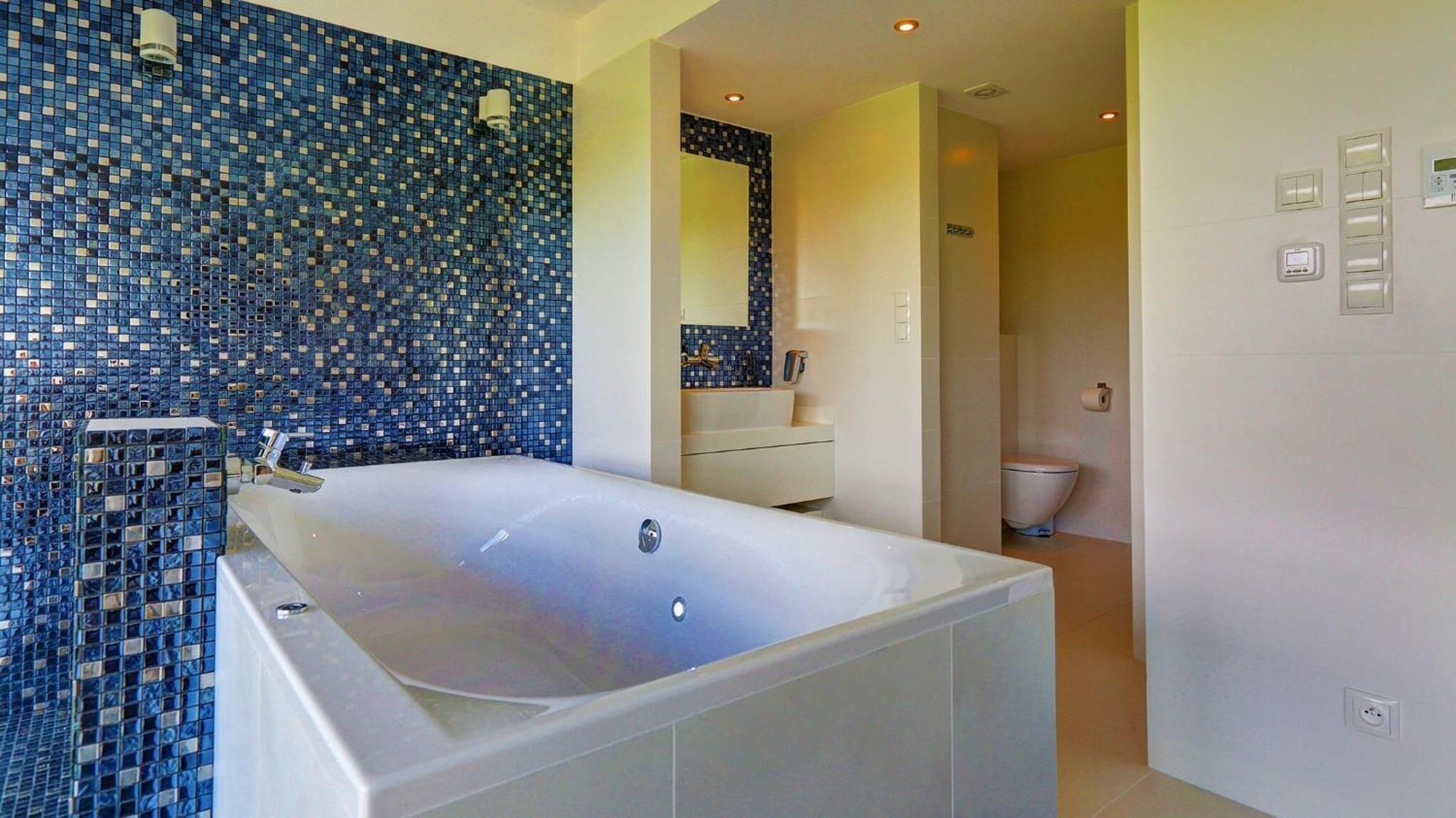 A modern bathroom with a large bathtub, a sink, and a toilet.