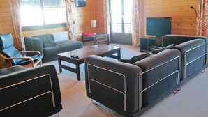 Un salon confortable avec un canapé, des fauteuils, une table basse et un téléviseur.
