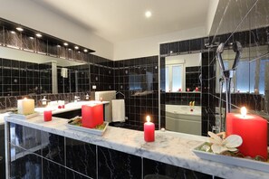 A modern bathroom with black marble tiles, a large mirror, and a vanity with red candles. - Florence Comfort B&B (Florence)