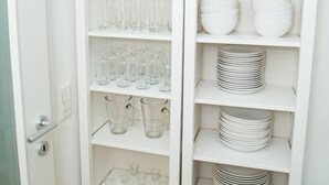 A white shelving unit with glassware and plates.